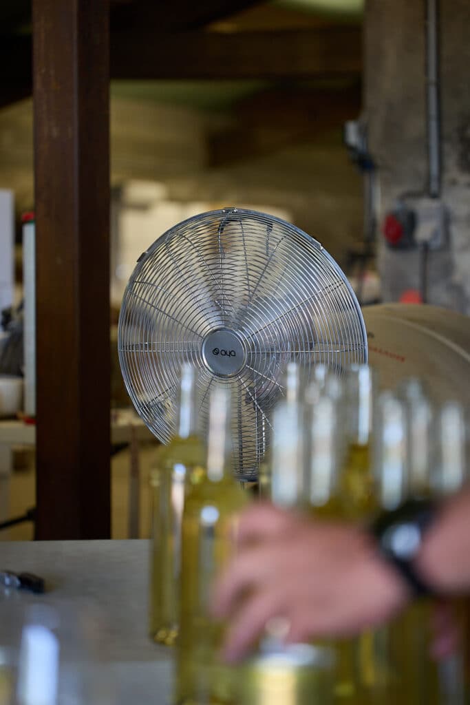 Ventilateur industriel derrière bouteilles en verre.